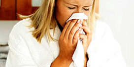woman sneezing into a tissue